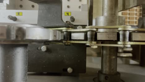 machine in a factory with pinion chain and gear rotates moves slowly drives something