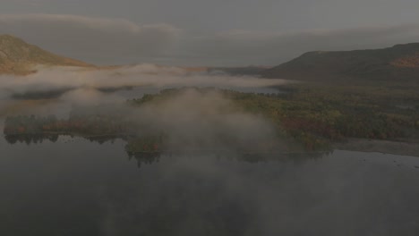 sunlight illuminates borestone mountain overlooking onawa-lake orbiting aerial