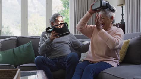 happy mixed race senior couple wearing vr headset and having fun at home