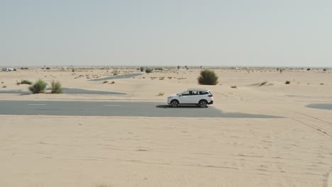 white suv driving through a desert landscape