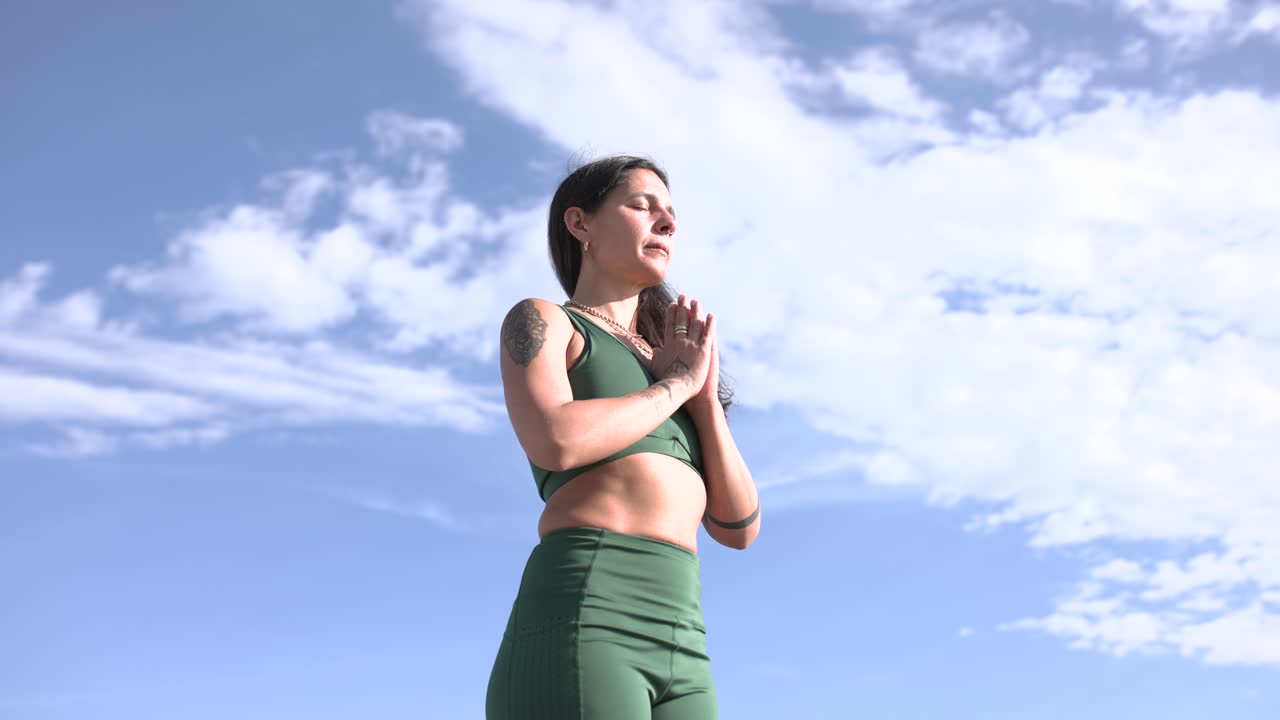 Woman practicing yoga outdoors with cloudy sky background