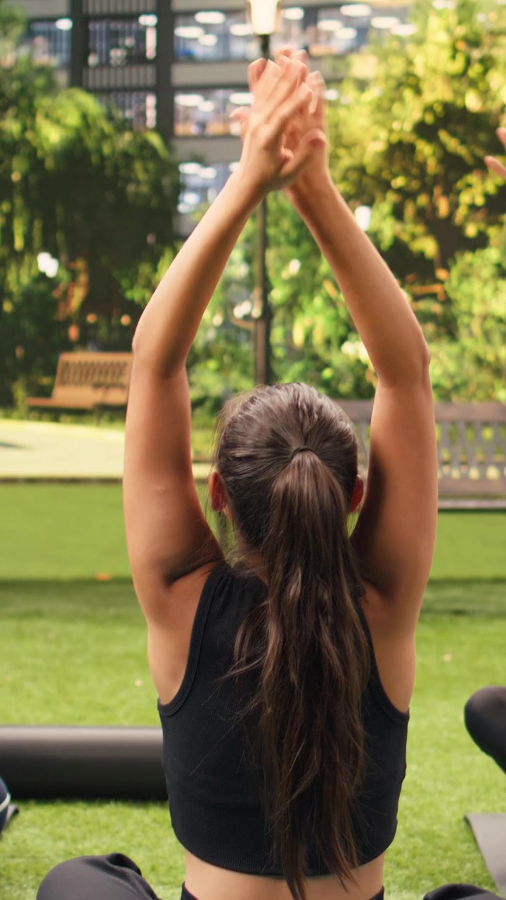 Video vertical de un instructor de yoga visto desde atrás guiando a los participantes en una meditación sentada