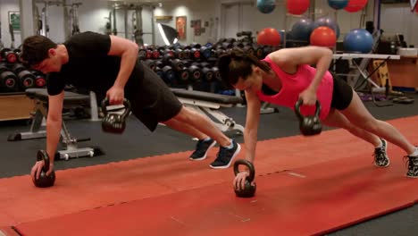 Pareja-Haciendo-Filas-De-Planchas-Ponderadas-En-El-Gimnasio