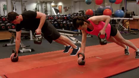 pareja haciendo filas de tabla ponderadas en el gimnasio