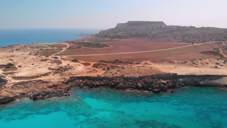 aerial footage of cape greco, highlighting the blue sea against the dry, brown terrain