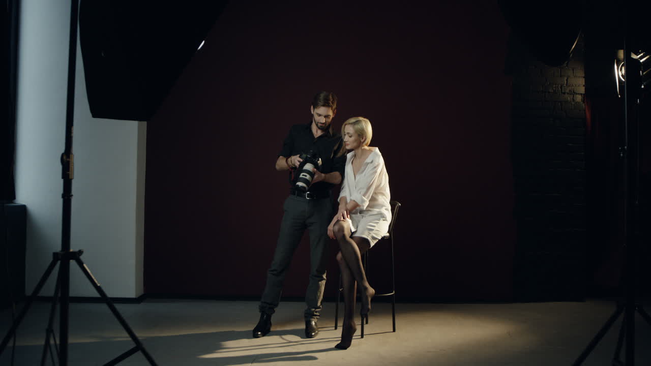 fotógrafo mostrando fotos en la cámara fotográfica a la modelo femenina en el estudio profesional