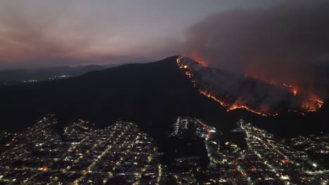 wildfire on a mountain overlooking a city at night