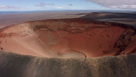 aerial view of a large volcanic crater with reddish-brown walls