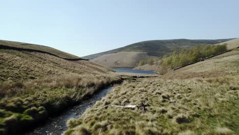 toma aérea y un primerísimo plano de un arroyo que lo sigue corriente abajo hasta la desembocadura del embalse kinder, peak district, reino unido