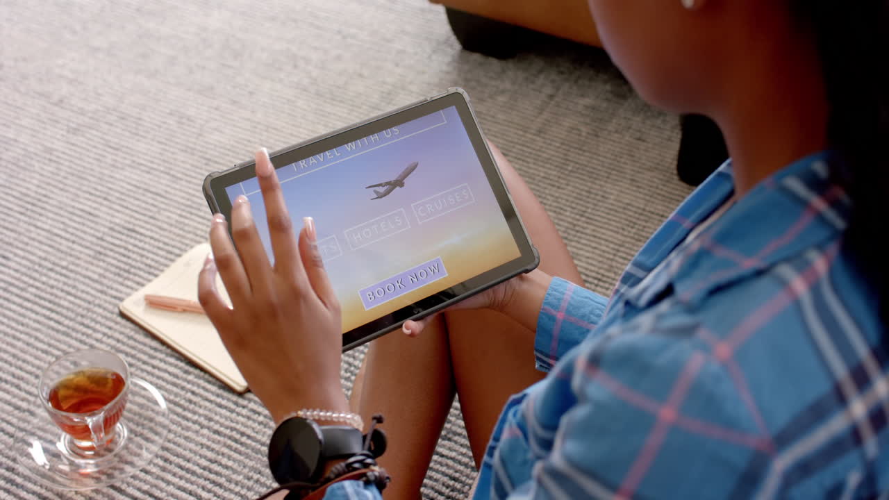 A young African American woman wearing blue plaid shirt is looking at a tablet
