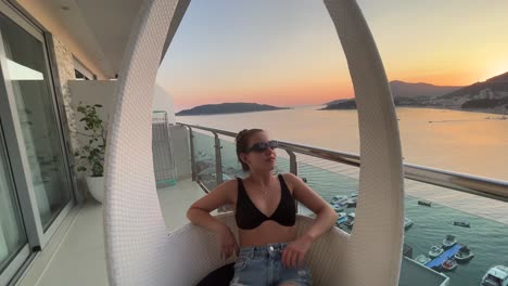 Young-girl-posing-for-the-camera-on-a-balcony-during-a-sunset-in-a-beautiful-small-fishing-town-in-montenegro-called-Rafailovici