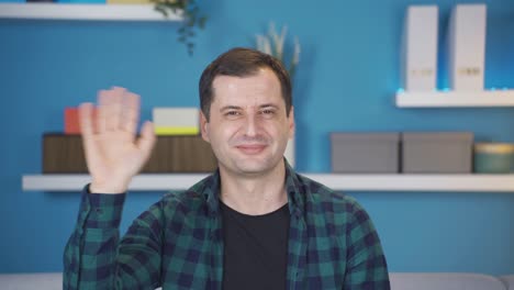 Portrait-of-positive-man-greeting,-waving,-saying-goodbye-while-looking-at-camera.