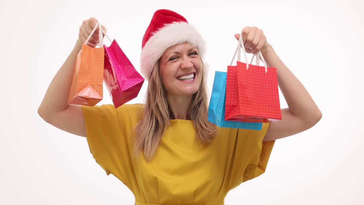 Happy Woman in Santa Hat Holding Christmas Shopping Bags