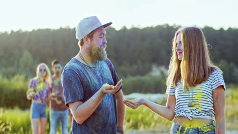 foto de retrato de la alegre pareja joven en pinturas coloridas durante las vacaciones de holi dándose cinco y sonriendo a la cámara