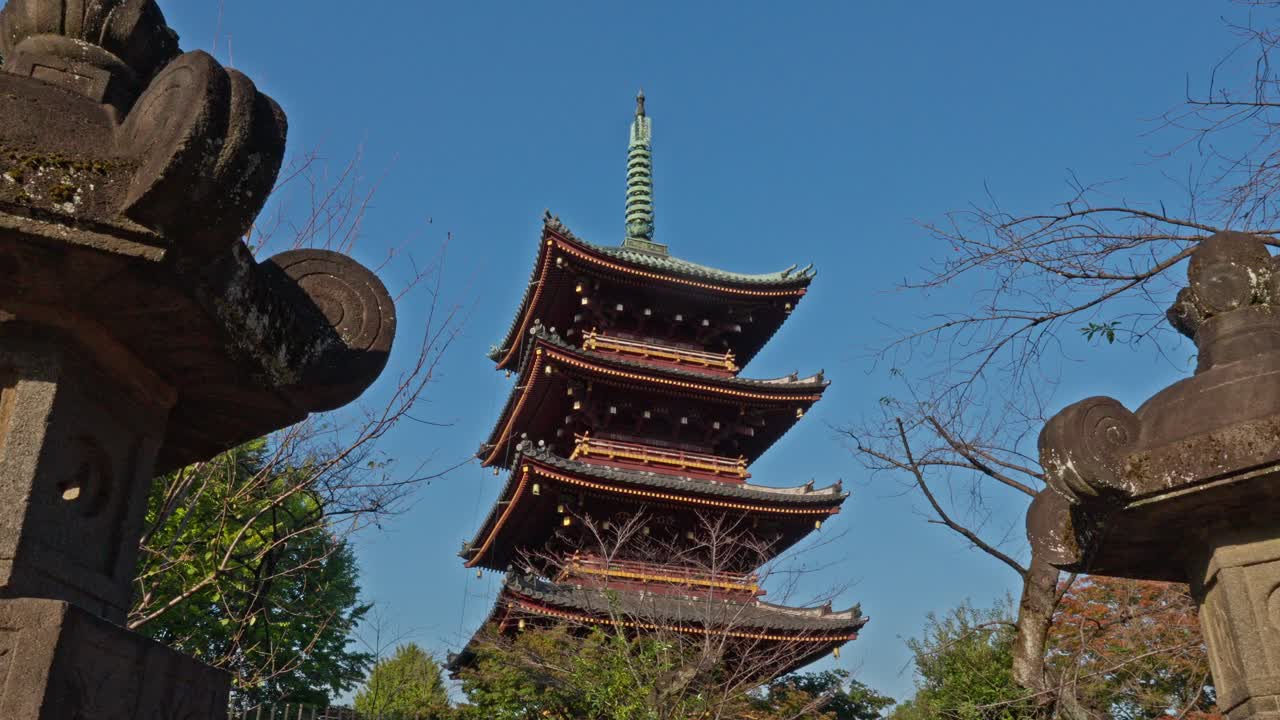 A majestic three-story Japanese pagoda stands tall against a vibrant blue sky, showcasing the timeless beauty and architectural grandeur of ancient Japan.