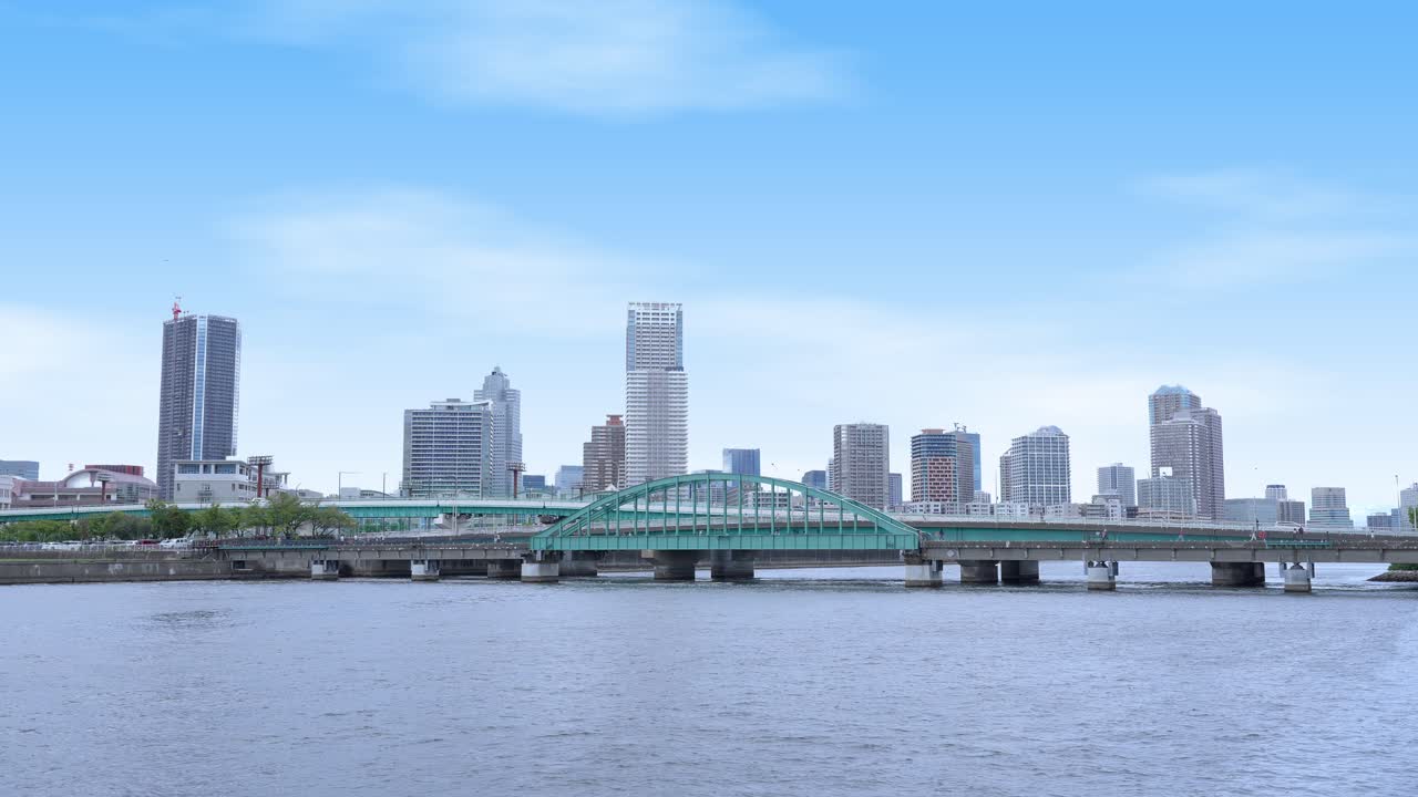A peaceful shot of the Harumi Railway Bridge and the Tokyo skyline with modern buildings under a clear sky