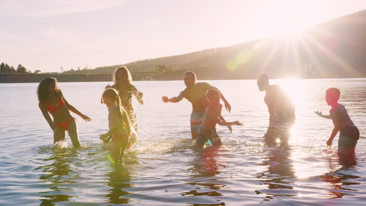 Two Families With Children Playing And Splashing In Lake