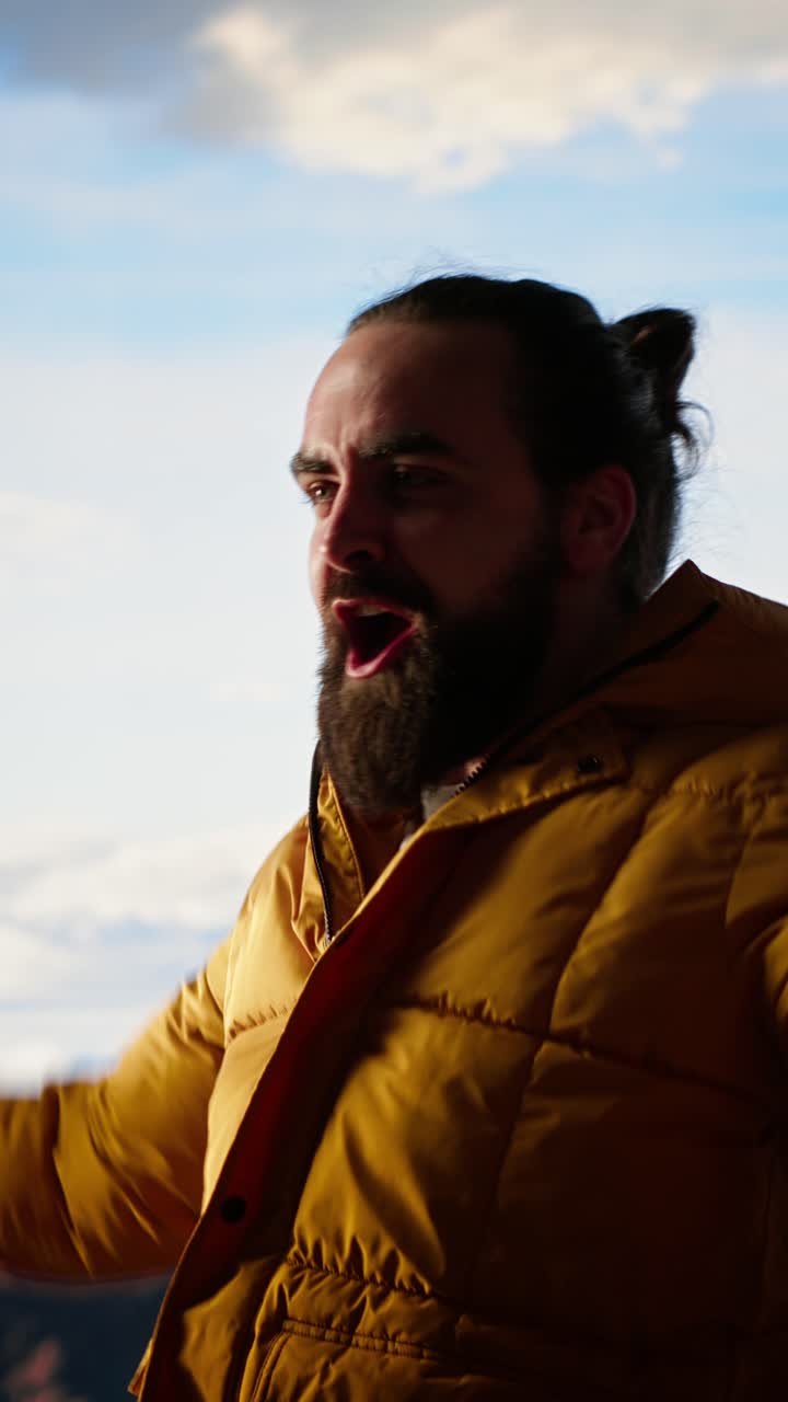 Uomo entusiasta con piumino giallo che grida all'aperto
