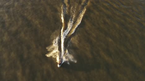 Aerial-view-rotating-around-jet-ski-during-sunset,-slow-motion