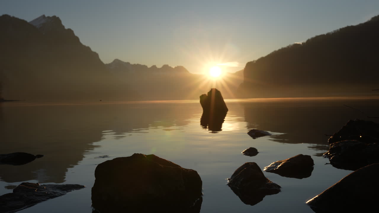 Early sunrise lights calm water and mountains near Walensee Switzerland