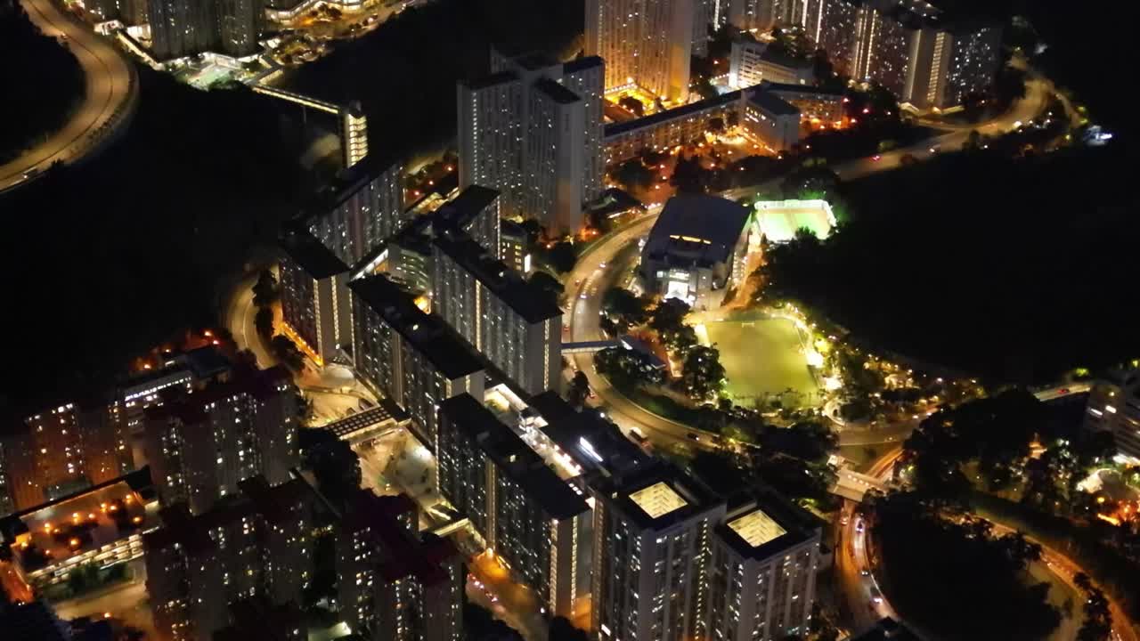 A breathtaking drone view of Hong Kong at night, showcasing the glowing skyline, busy harbor, and vibrant city lights from above.