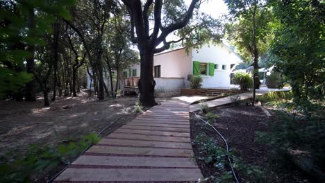 slow establishing shot of a rural villa in france along a wooden boardwalk