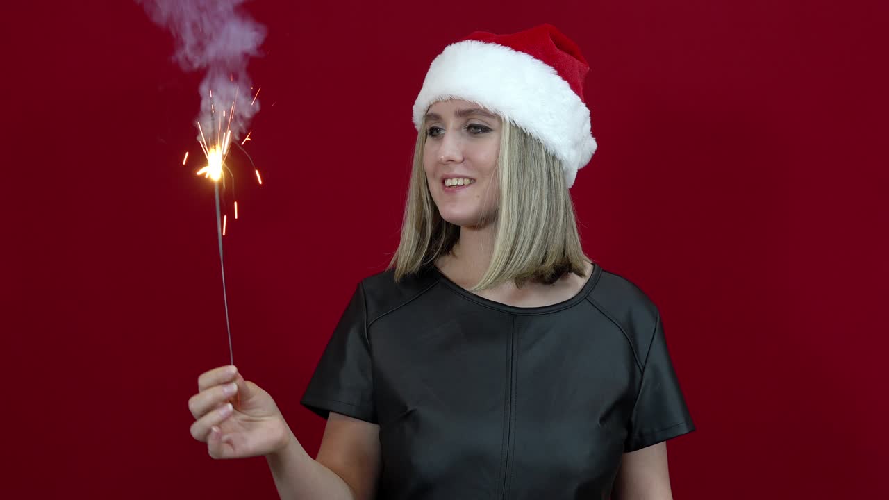 Woman with santa claus hat on red background holding bingala fire