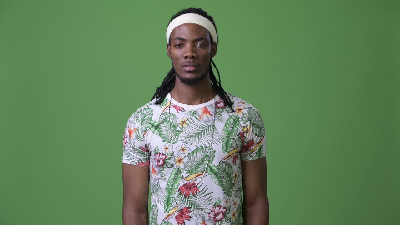 joven hombre africano guapo con dreadlocks contra un fondo verde