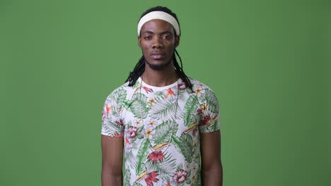 young handsome african man with dreadlocks against green background