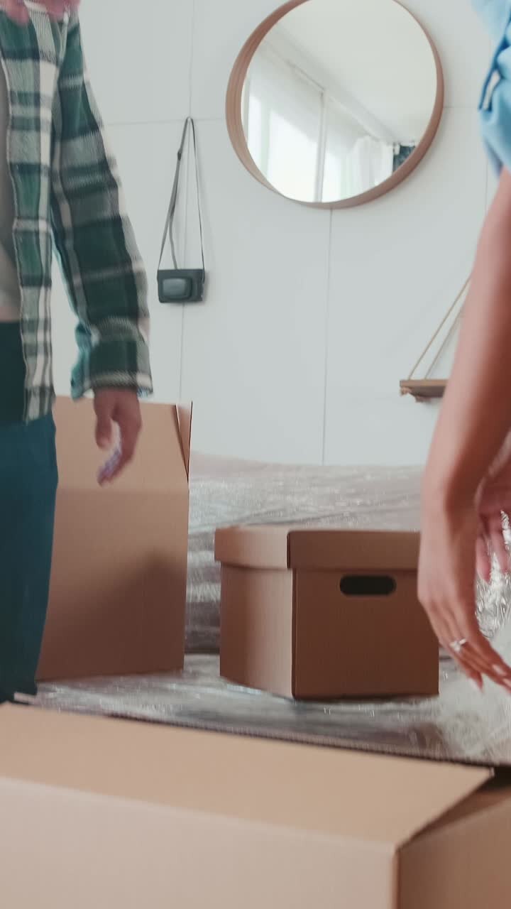 Young woman and man together carrying boxes to purchased apartment