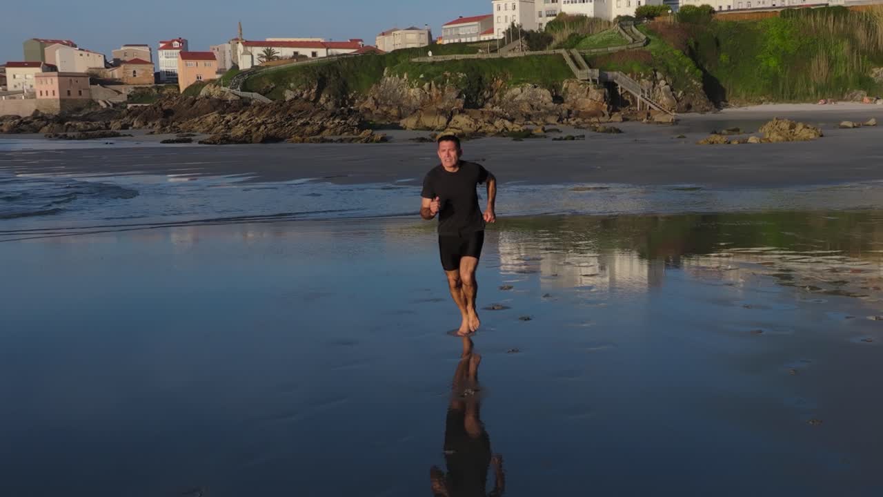 A Lone Man Is Running Barefoot On The Shore Of Praia de Caión, Spain. Slow Motion Shot