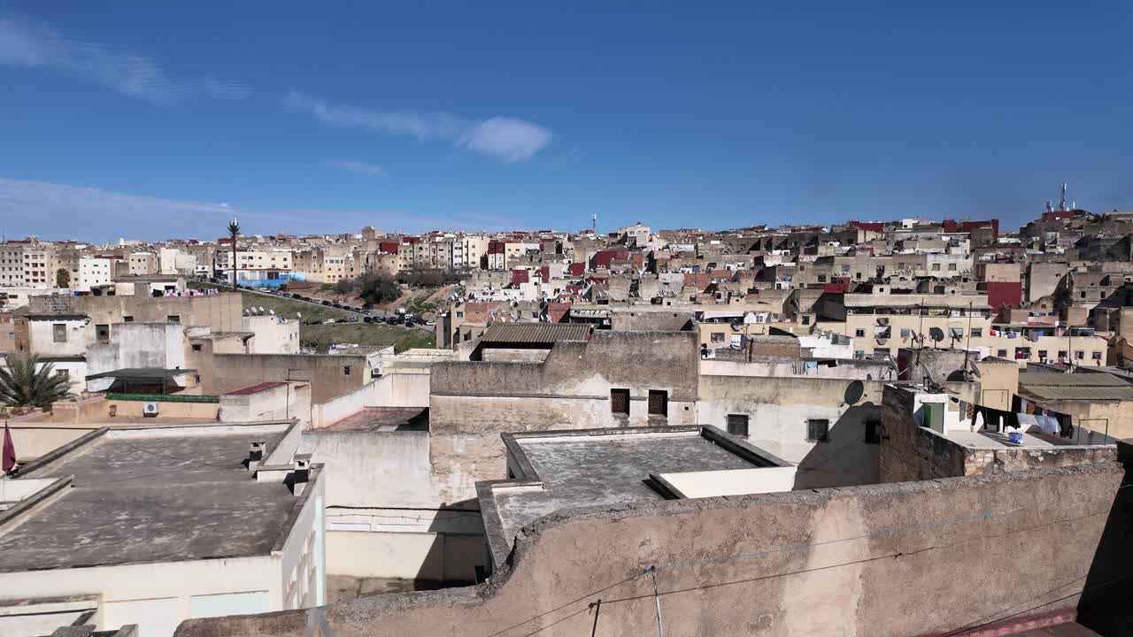 Cityscape of Fez featuring traditional buildings and vibrant rooftops under a clear blue sky, capturing the essence of Morocco's rich culture