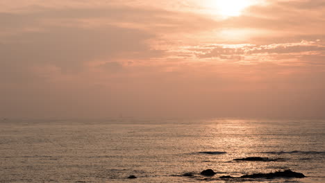 Timelapse-of-sunset-behind-clounds-on-beach-with-vessels-passing-by-in-Porto,-Portugal