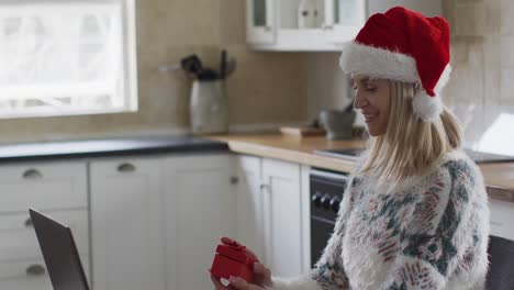 Woman-opening-gift-box-while-having-a-video-call-on-laptop