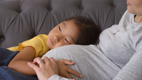 madre embarazada relajándose en el sofá con su hija