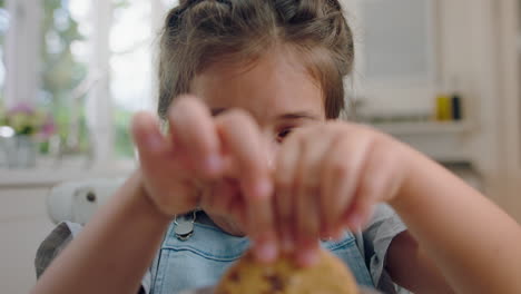 cute little girl eating cookie dipping biscuit into hot chocolate enjoying delicious treat at home in kitchen