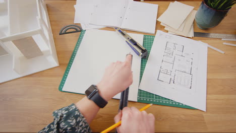 pov filmado con una arquitecta cortando y haciendo un modelo de edificio en el escritorio