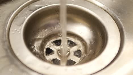 close-up of water draining into a stainless steel sink