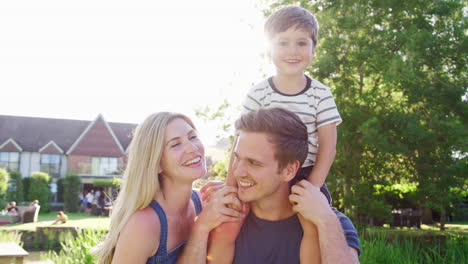 retrato de família com o pai dando passeio do filho sobre os ombros no jardim do pub de verão