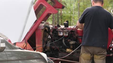 static shot of a mechanic repairing an old tractor motor, on a sunny, summer day, in ostrobothnia, finland