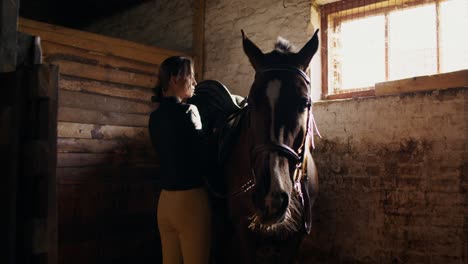 mujer preparando un caballo en un establo
