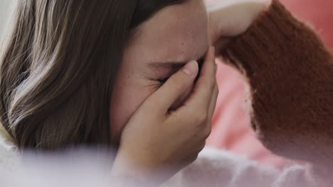 Sad-caucasian-teenage-girl-sitting-on-bed-and-crying-at-home