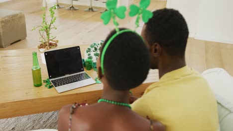 African-american-couple-making-st-patrick's-day-video-call-wearing-deely-boppers-waving