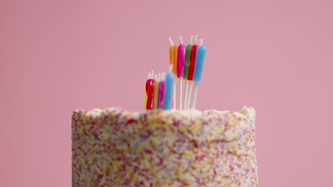 foto de estudio de pastel de cumpleaños giratorio cubierto con decoraciones y velas que deletrean feliz cumpleaños 4