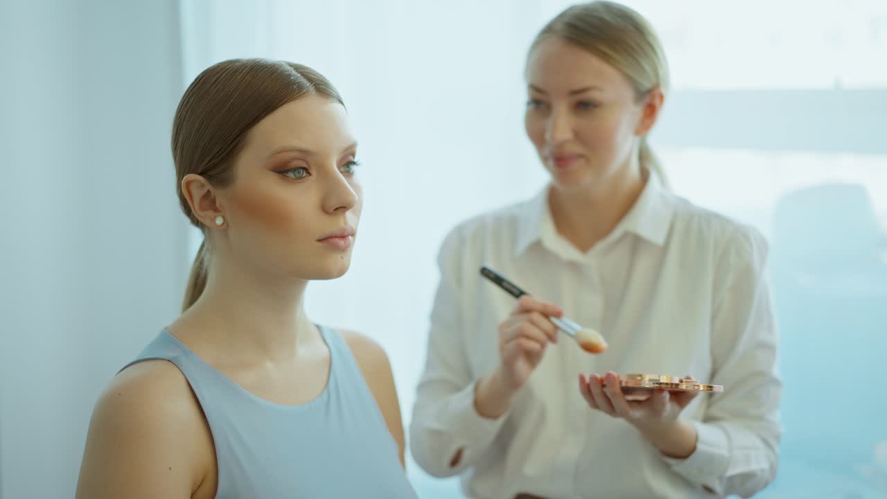 메이크업 아티스트가 모델에게 메이크업을 하고 있습니다.