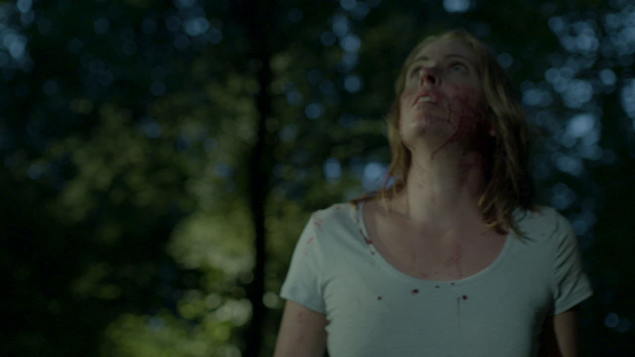 mujer perdida y ensangrentada mirando alrededor en el bosque por la noche