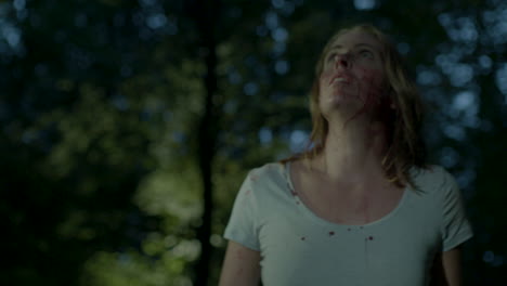 mujer perdida y ensangrentada mirando alrededor en el bosque por la noche