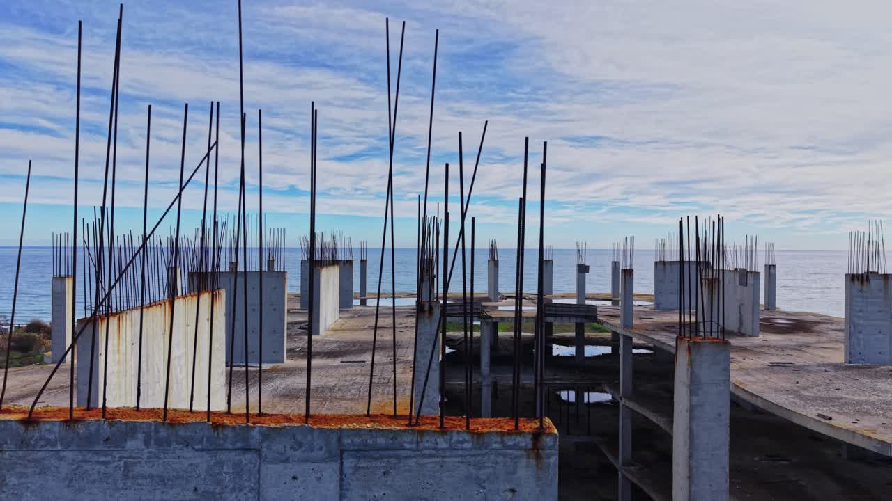 Construction site overlooking the ocean with rebar and cloudy sky