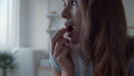 Woman enjoying strawberries in kitchen