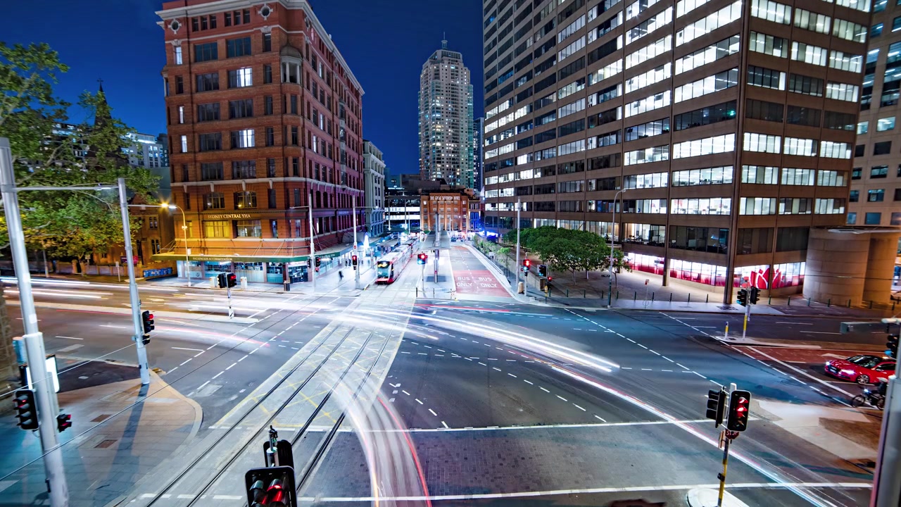 Stadtverkehr an einer belebten Kreuzung bei Nacht, Weitwinkel, Sydney.